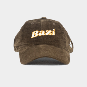 Frontansicht der braunen Cord-Cap mit gebogenem Schirm. Auf der Vorderseite ist der Schriftzug "Bazi" in weißer Schrift und orangener Umrandung gestickt, seitlich befindet sich ein kleines weißes Logo mit den Buchstaben "bc"