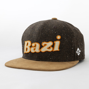 Dunkelbraune Cap mit hellem Schirm in Wildlederoptik. Auf der Vorderseite ist der Schriftzug "Bazi" groß in cremefarbener Stickerei mit orangem Rand zu sehen. An der Seite befindet sich ein kleines weißes Logo.